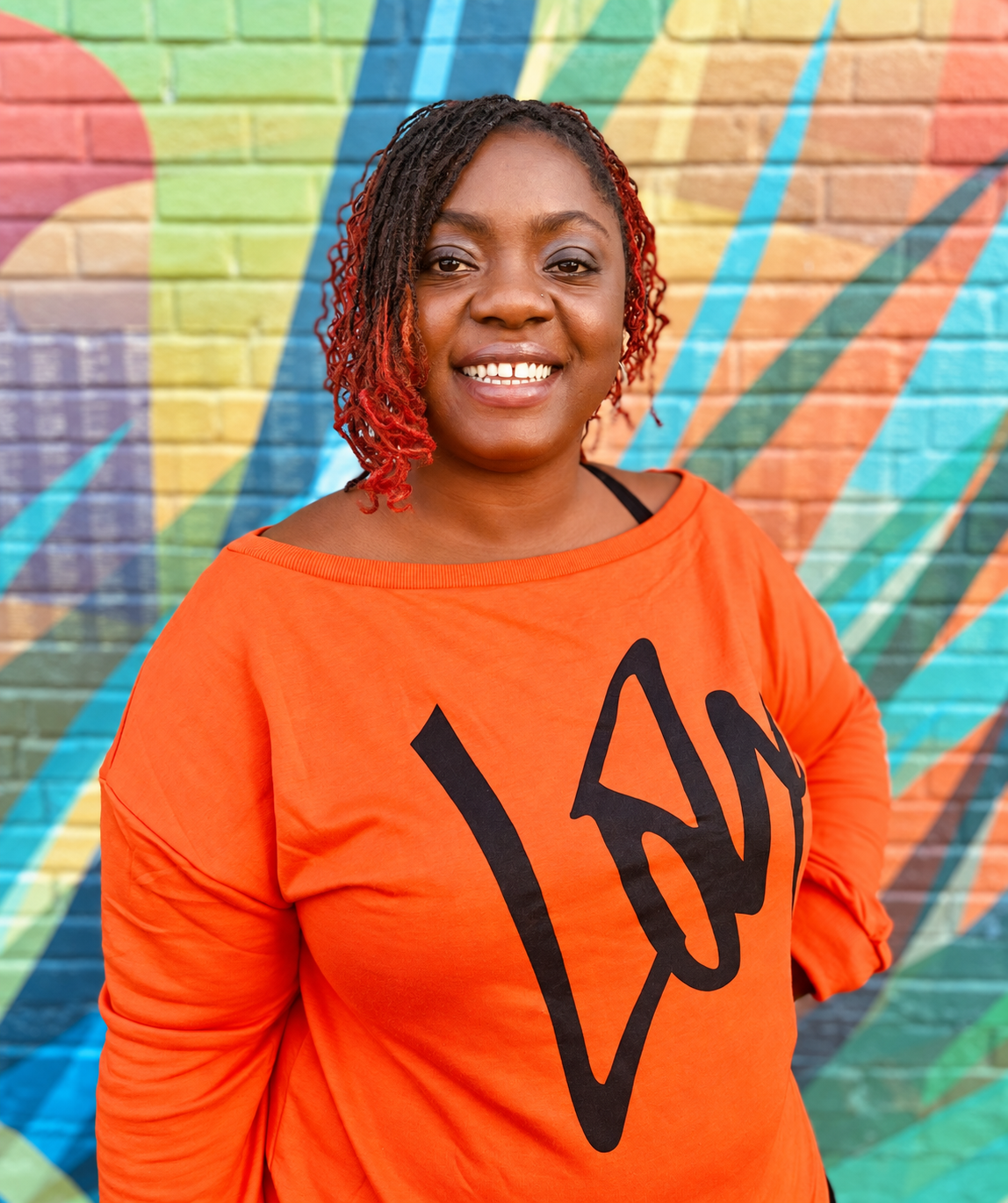 Angenette Burns smiling in front of a colorful mural
