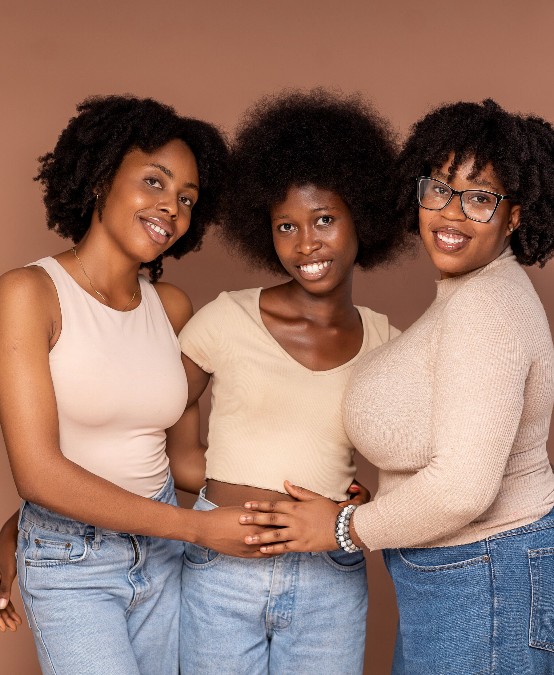 Three Black women with natural hair standing together and smiling